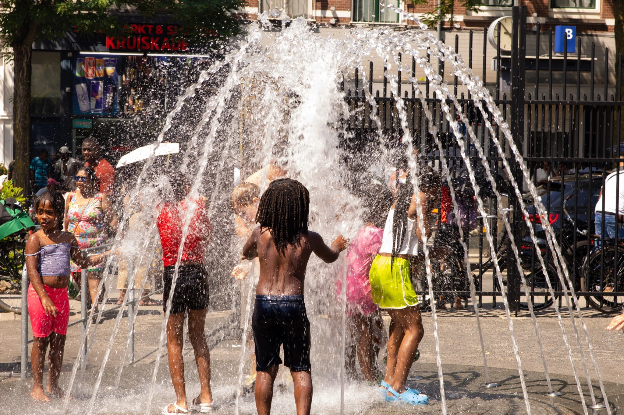 Kinderen spelen en verkoelen onder een fontein tijdens een zomerse festivaldag